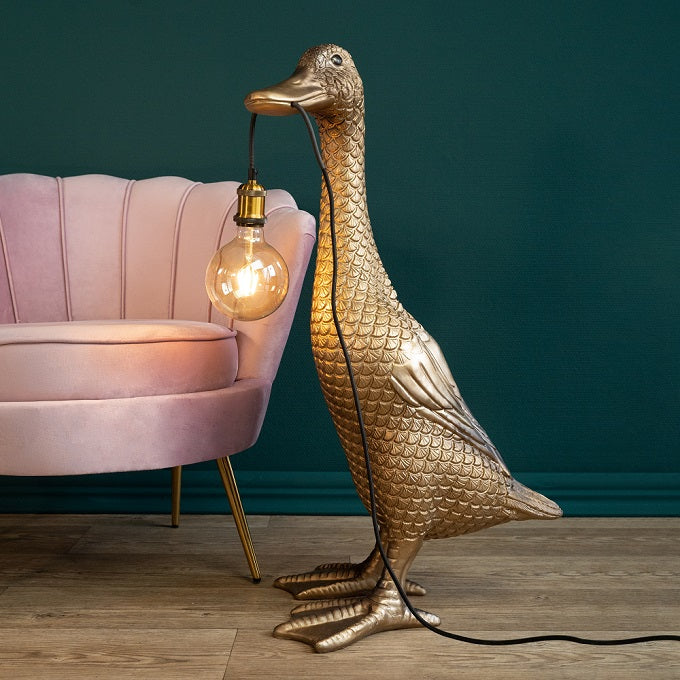 Stehleuchte Ente Ducky in Gold von Werner Voß neben einem Sessel