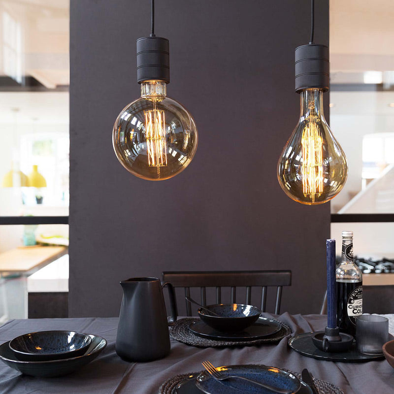 Calex Mega-Globe G200 High Lumen in Gold als Pendel über einem gedeckten Esstisch
