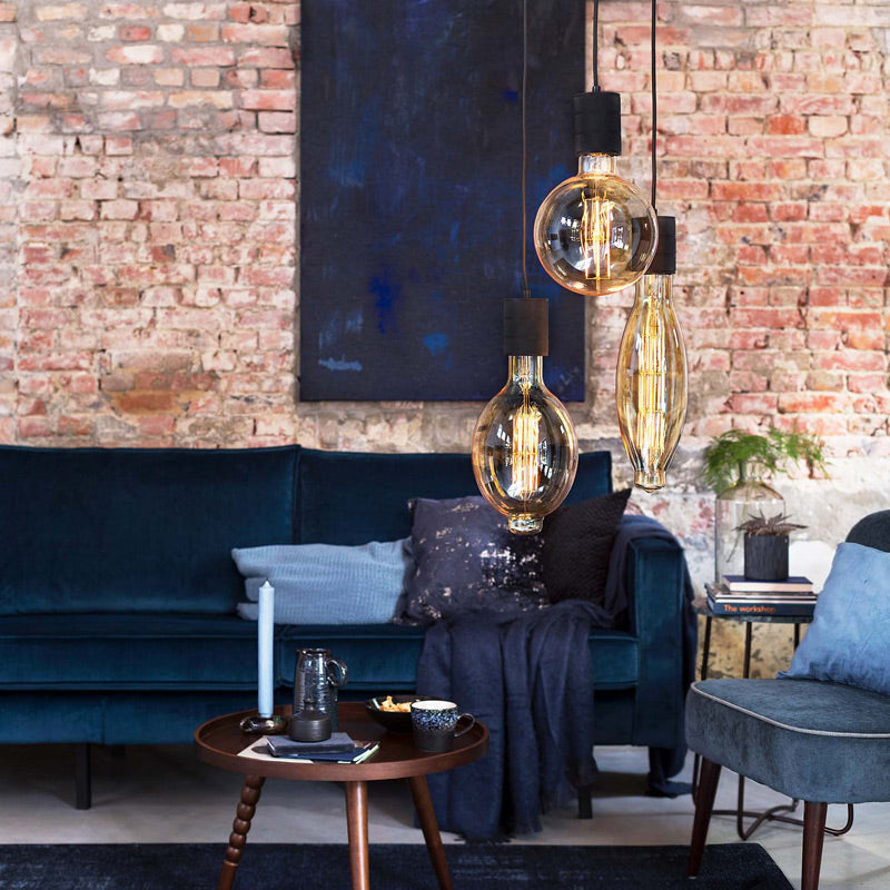 Calex Mega-Globe High Lumen in Gold im Wohnzimmer mit Backsteinwand